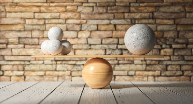 Wooden Scale Balancing One Large Ball Against Four Smaller Ones - Symbolizing the Key Differences Between Funds and Syndications