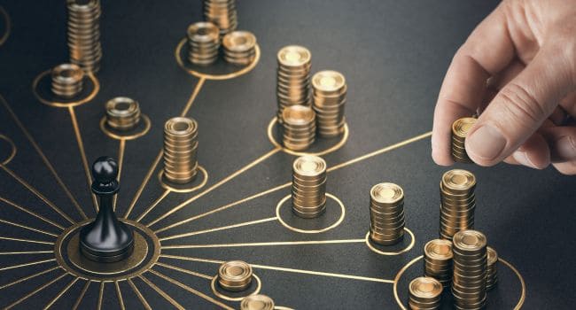 Man putting golden coins on a board representing diverse investment strategies and asset allocation.